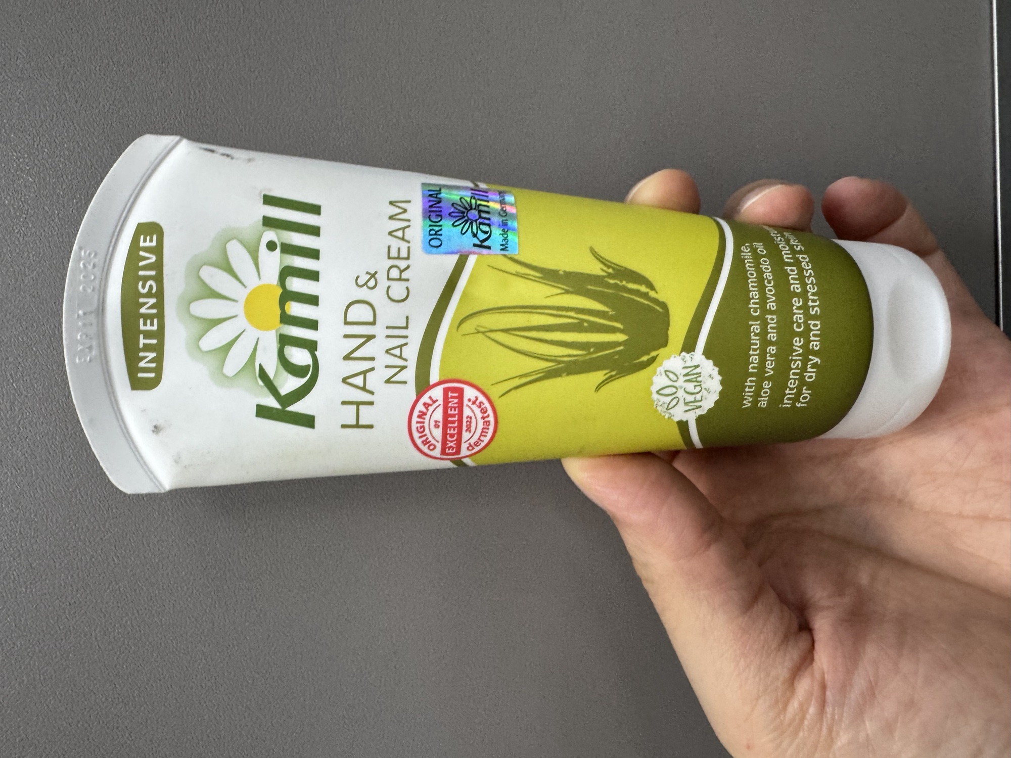 管身正面手持。INTENSIVE 綠標、洋甘菊與蘆薈插畫、VEGAN 標、ORIGINAL Kamill Made in Germany 雷射標與 dermatest EXCELLENT 標。
