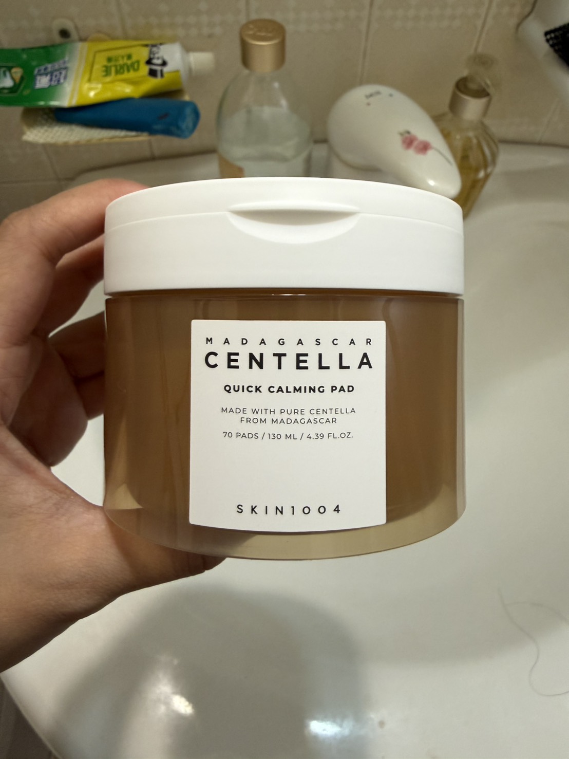 罐身正面。棕色透明罐、白蓋，貼紙印 MADAGASCAR CENTELLA／QUICK CALMING PAD／70 PADS / 130 ML / 4.39 FL.OZ.／SKIN1004。