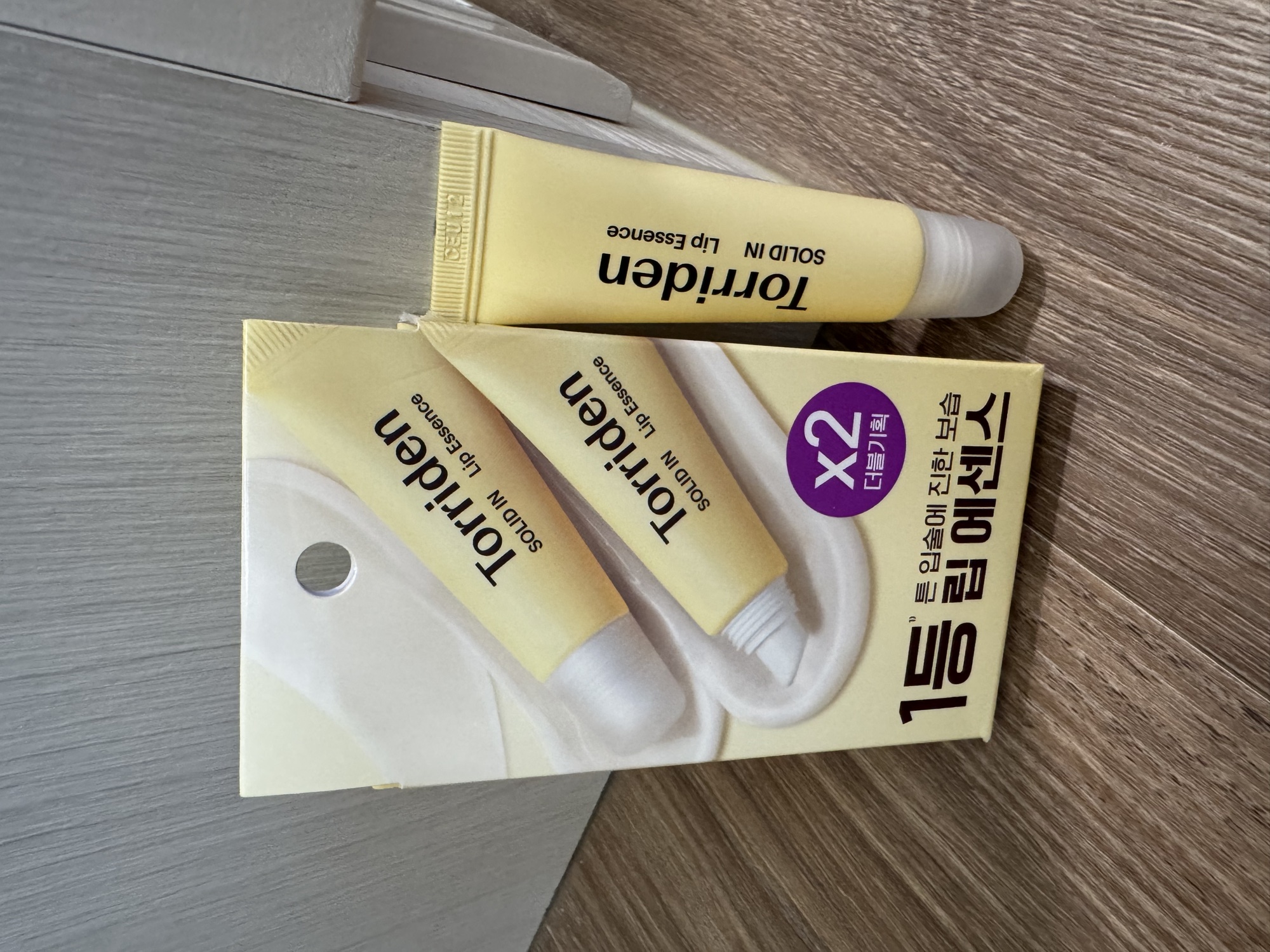 外盒正面與管身。Torriden SOLID IN Lip Essence、x2 더블기획 紫標、1등 립 에센스。