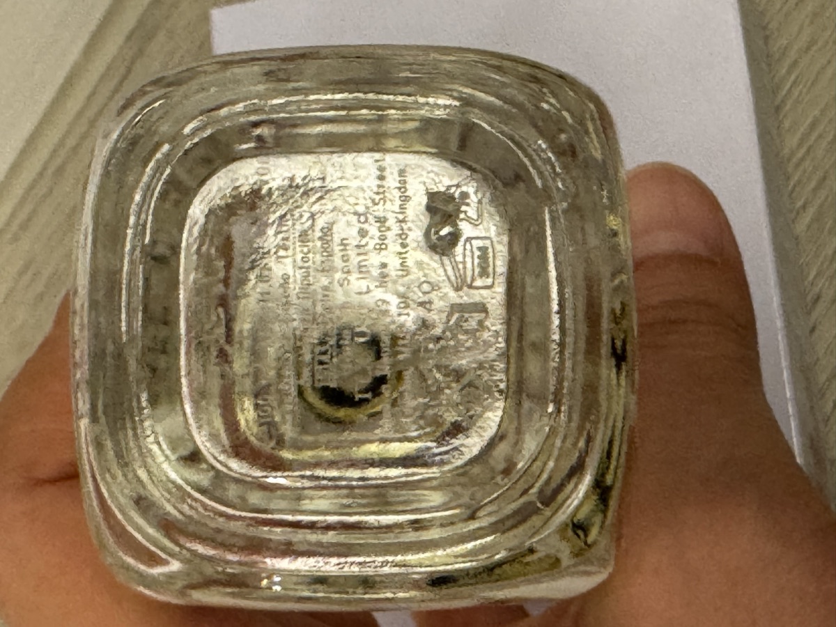 瓶底壓印特寫。玻璃壓紋，可辨識 United Kingdom 與開蓋圖示輪廓，圖示內的月數讀不出來。