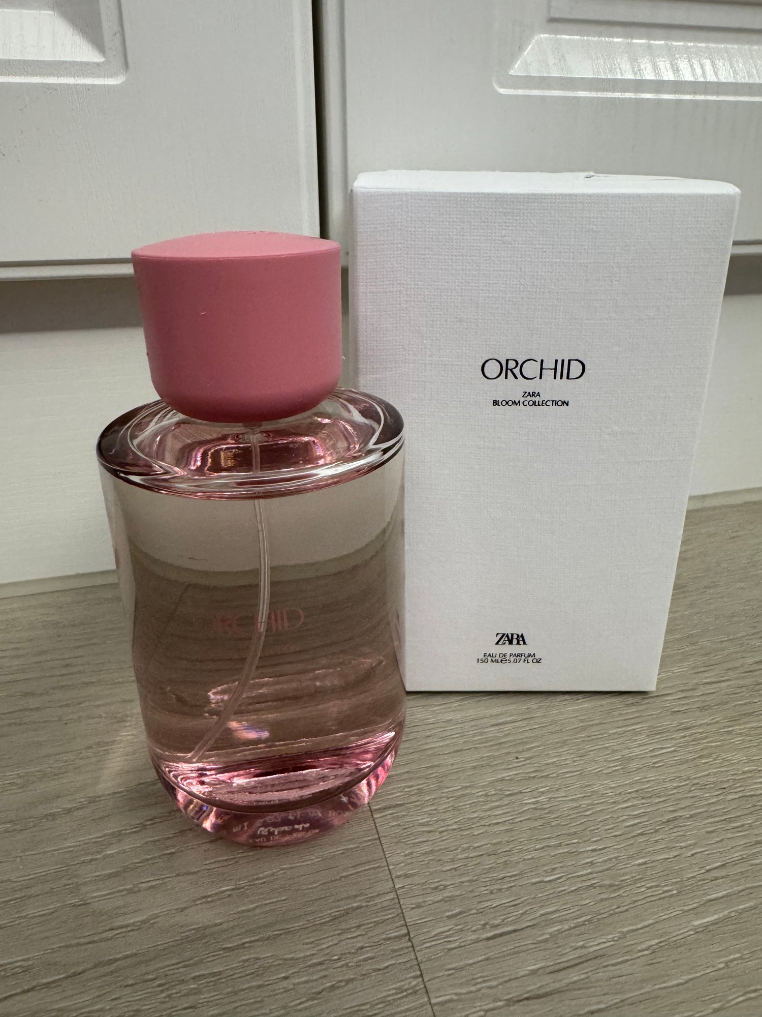 瓶身與外盒正面。粉色瓶蓋，玻璃瓶身印 ORCHID，瓶中液體帶粉色。